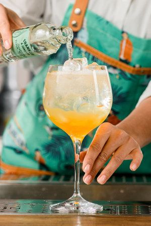 UKRAINE, KYIV - MARCH 12, 2021: close-up of glass with cold bright cocktail in which bartender pouring tonic from bottleのeditorial素材