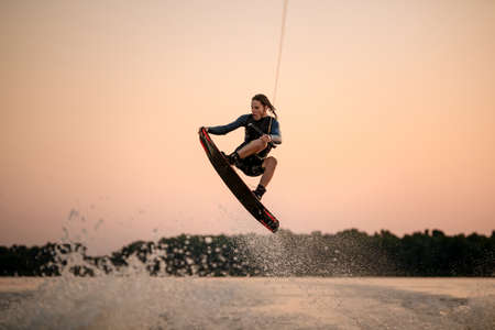 active strong man making trick in jump time with wakeboard on sky background.の写真素材