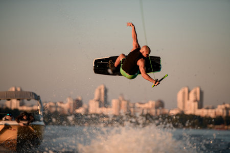 gorgeous view of athletic man making extreme jump showing trick in the air on wakeboard against the skyの写真素材