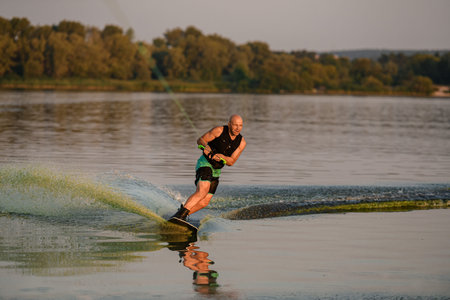 energy strong man engaged in water sport and balancing on water surface on a wakeboard