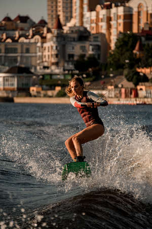 pretty woman in wetsuit having fun on the wakeboard on river waveの写真素材