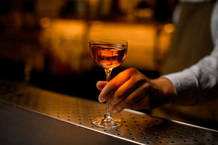 beautiful wine glass with drink on steel bar surface and male hand holds it.の写真素材