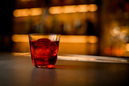 selective focus of transparent glass of cocktail with piece of ice stands on a bar counterの写真素材