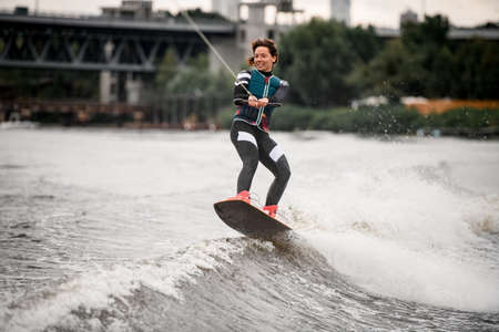 young sportive woman in wetsuit professionally engaged in wakeboardingの写真素材