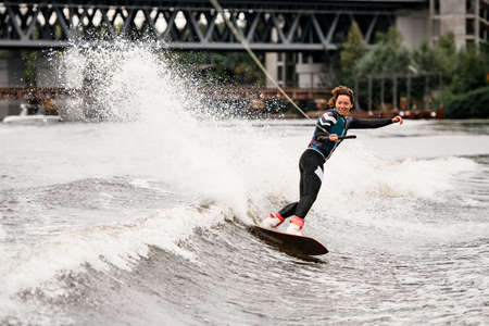handsome woman in wetsuit engaged in wakeboarding on summer dayの写真素材