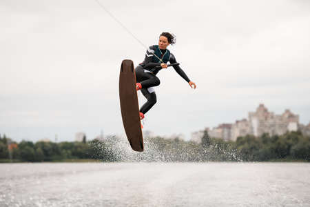 young energetic woman doing extreme jumps over the wave on a wakeboardの写真素材