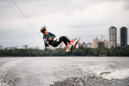 young woman holds rope and extreme jumping over the splashing wave on wakeboardの写真素材