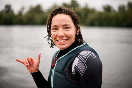 Portrait of young smiling woman with wet hair in swimwear who shows hand gesture.の写真素材