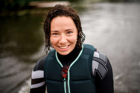 portrait of cheerful attractive woman with wet curly hair in swimsuit and vestの写真素材