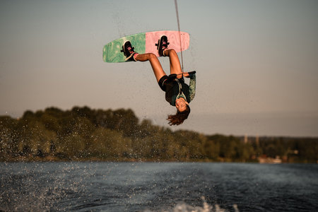 Beautiful view of female rider holding rope and making jump on wakeboard. Water sports activity.の写真素材