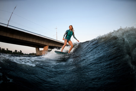active woman wakesurfer riding down the great splashing river wave.の写真素材