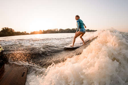 fit woman masterfully riding wakesurf on splashing river water. Active water sportsの写真素材