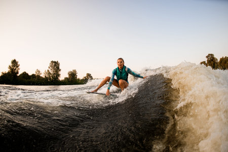 beautiful woman sits on surf and rides the wave and touches the wave with one hand