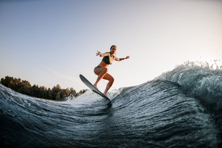 handsome fit woman making trick and jump with wakesurf on splashing wave.の写真素材