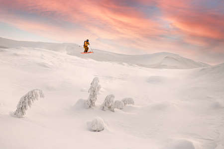 wonderful view of snowy mountain slope and male skier jumping airの写真素材