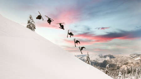 amazing view of snowy mountain slope and skier making trick in jumping through airの写真素材