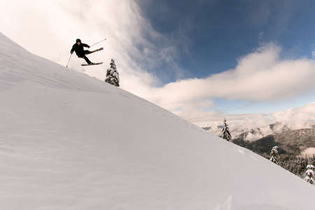 beautiful view of snowy mountain slope and skier jumping airの写真素材