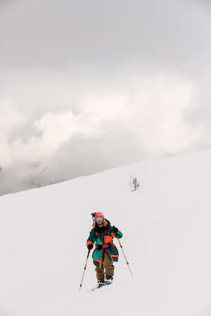 front view of joyful man skier walking along snowy hill trailの写真素材
