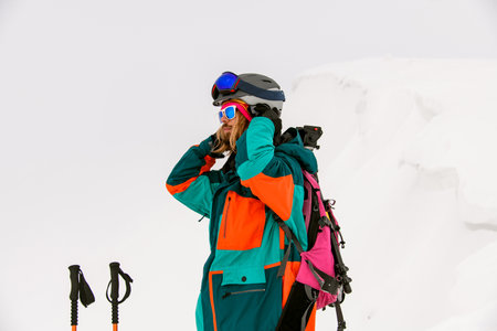 man skier in bright colorful ski suit and sunglasses against background of snowの写真素材