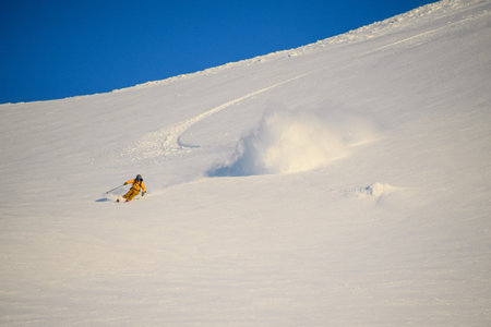 Wonderful view of freerider riding fast through the snow down the mountain slope.