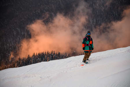 athlete in ski suit stands on snowboard on snow-covered mountain slopeの写真素材