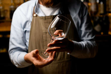 male hands gently hold empty clear wine goblet glass.の写真素材