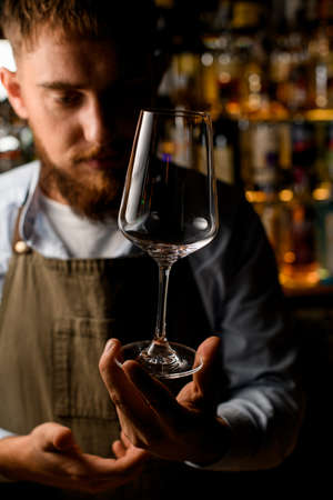 Front view on beautiful clean empty transparent wine goblet in male hand.の写真素材