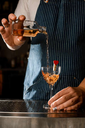 great view on wineglass decorated with heart and hand pouring drink into itの写真素材