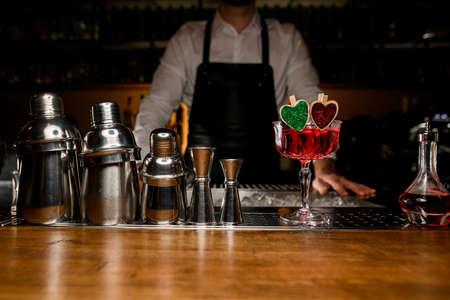 Glass with delicious tasty red alcohol cocktail decorated with small wooden green and red heartsの写真素材
