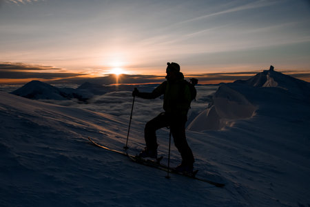 silhouette of a skier against the backdrop of the sky and sunrise