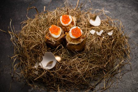 great view of boiled eggs stuffed with red caviar and serving in golden shell on decorative hayの写真素材