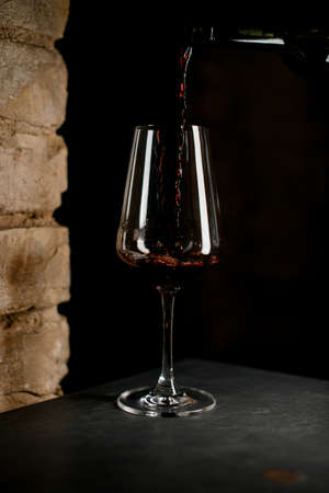 close-up of wine glass into which red wine is poured from a bottle.の写真素材