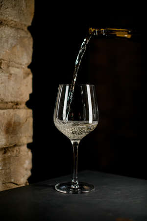 wine glass into which white wine is poured from a bottle.の写真素材