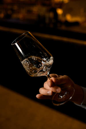 close-up of beautiful wine glass with a splashed drink in male handの写真素材