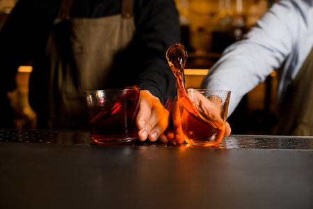 glasses with bright splashing cocktails on the bar and males hands