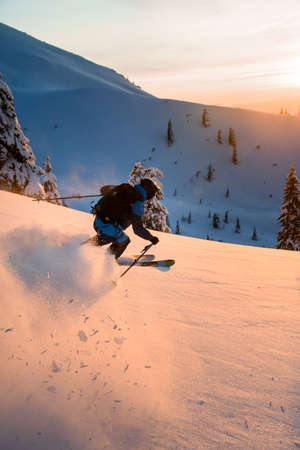 Man freerider fast sliding down snow-covered slopes on fresh powder snowの写真素材