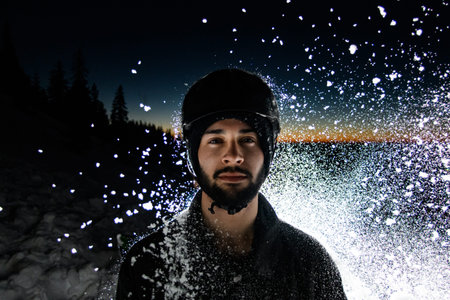 portrait of man in ski helmet on background of dark sky and splashing snow.