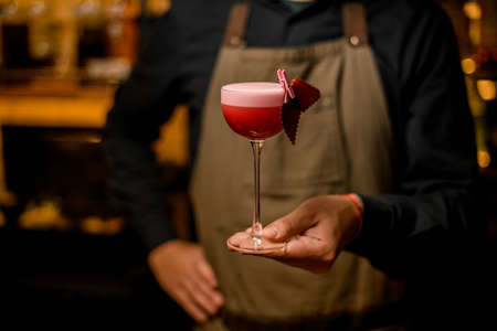 Bartender holding in hands pink cocktail decorated with fruit marshmallow.の写真素材