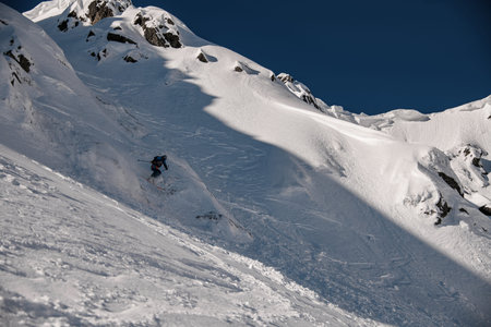 Great view of the rocky snow-covered mountain slope and the skier slides down