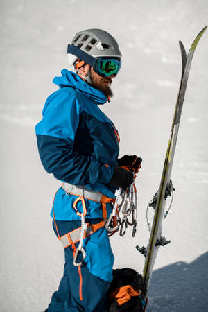 Side view of man skier in ski suit and helmet with climbing harness wearing on.の写真素材
