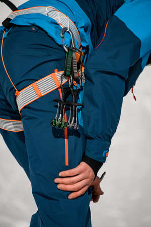 Close-up of the body part of a man in ski suit with climbing harness wearing on.の写真素材