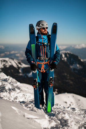 full-length portrait of man with skis against the background of a winter mountain landscape