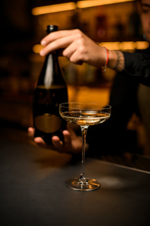 beautiful wine glass with drink on bar. Hand of a man bartender with a bottle in the backgroundの写真素材