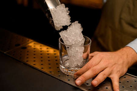 close-up on transparent clean glass into which crushed pieces of ice are pouredの写真素材