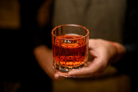 selective focus of old-fashioned glass with cold alcoholic drink in male handの写真素材