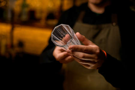 hands of bartender accurate hold tall cocktail glass. Focus on the fingersの写真素材