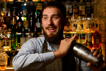 portrait of smiling bearded bartender with a shaker in his handsの写真素材
