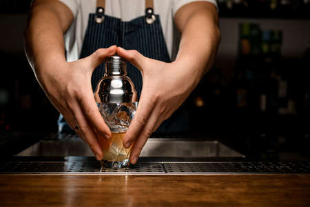 close-up of shaker covered by the hands of man bartenderの写真素材