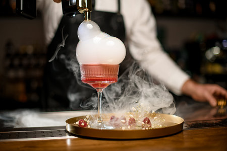 Close-up of glass with pink alcoholic cocktail which decorates by bubbles with smoke