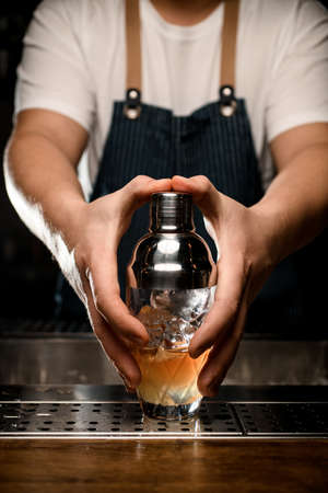 Hands of barman professionally holds glassy shaker by two handsの写真素材